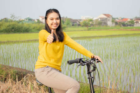 beautiful young asian women cycling in a very cool and comfortable countrysideの写真素材