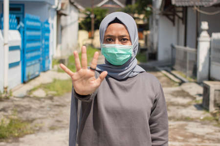Asian women in hijab wear masks to protect and show stopped hand movements to stop the corona virus...