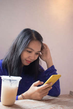 a beautiful woman is playing a smartphone in a cafe