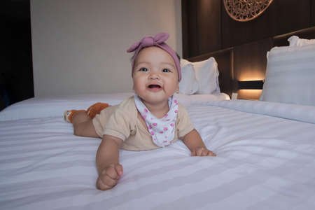 cute and adorable baby girl is laughing and stylish in front of the camera in the bedroom