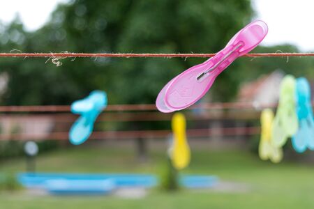Clothespins clipped on a clothesline, garden with pool in backgroundの写真素材