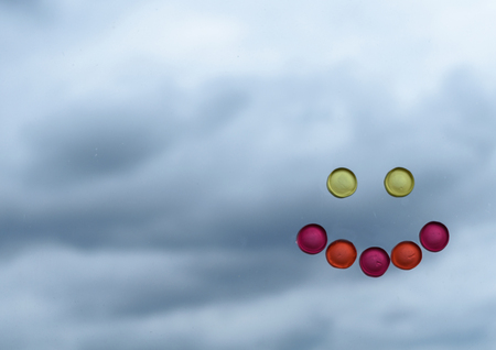Smiley face made of sweet candy contrasting with clouded moody background
