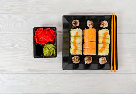 Delicious sushi on a white texture board. Sushi set on a black plate on a white wooden background.の写真素材