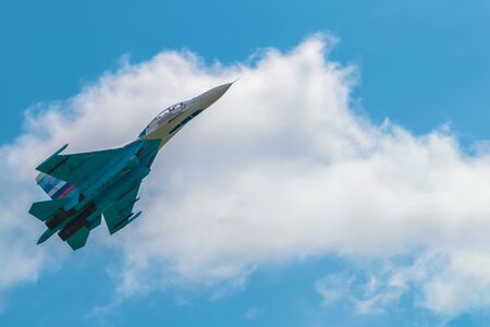 NOVOSIBIRSK, RUSSIA - JULY 26, 2015: Russian fighter plane Su-27 in blue sky against white cloud
