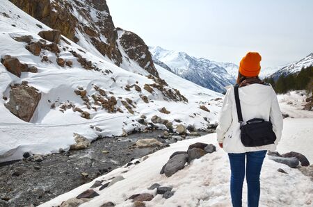 girl standing back over background of winter mountains panoramaの写真素材