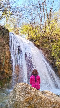 Girl standig over background of waterfall in forestの写真素材