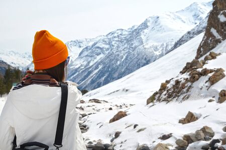 girl standing back over background of winter mountains panorama