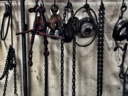 dirty chain and factory tools were hanging on old and grunge steel plate wall,dramatic tone,abstract designの写真素材