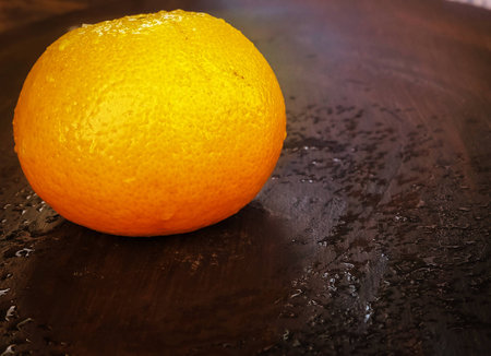 Close up the fresh orange with water drops put on wooden desk,in abstract art design,blurry light background.の写真素材