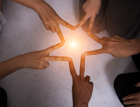 Create finger is star shape from teamwork.United hands team,the collaborate project,warm light tone at the middle of the star,blrry light around.の写真素材