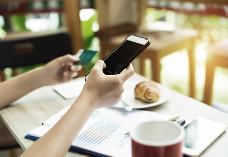 In selective of mobile phone was holding by right hand and blurred credit card at the left hand,for shopping online and payment.warm light tone,blurry light around.の写真素材