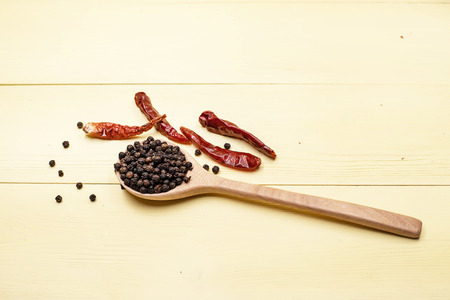 The dried chili put beside wooden spoon with pepper seed,on yellow wooden timber board,blurry light...