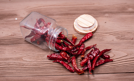 Closeup dried pepper group,put beside the opened glass bottle,on grunge surface timber board,blurry...