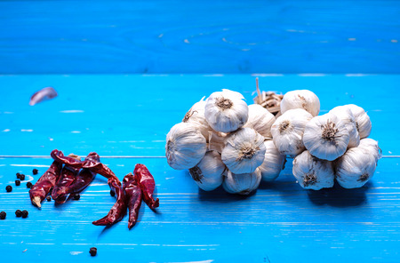 The group of garlic put beside dried pepper,on blue timber board,blurry light design backgroundの写真素材