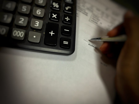 Close up of a black calculator with a pen and a blank sheet of paperの写真素材