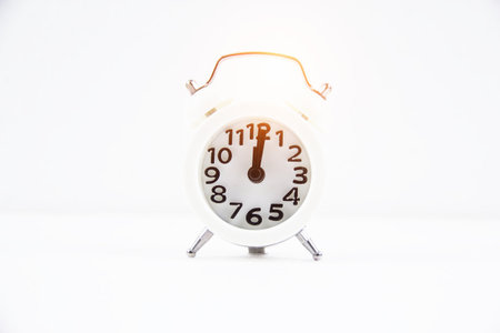 The white alarm clock put on white background.warm light tone,blurry light around