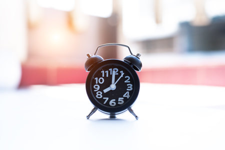 Closeup black alarm clock,the dial is eight o'clock,blurry light design background