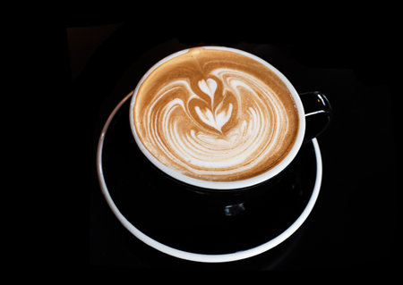 The cappuccino in black ceramic cup,on black table
