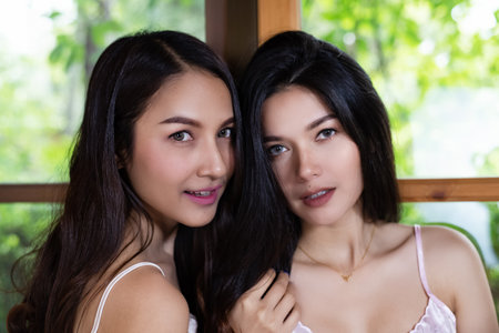 Two happy ladies are smiling beside window,beauty portrait,blurry light aroundの写真素材