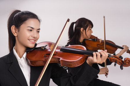 The lady with violin is playing song in front of the lady is playing viola,blurry light around.の写真素材