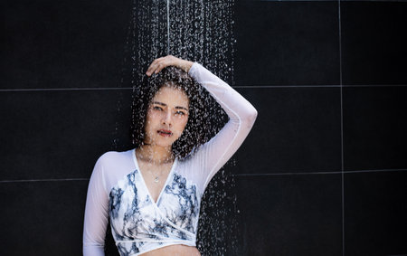 The beauty lady is posing at the back of the shower,water is flowing down,abstract art design backgroundの写真素材