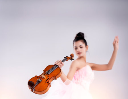 In selective focus of wooden violin was holding by beauty lady hand,blurry light design backgroundの写真素材