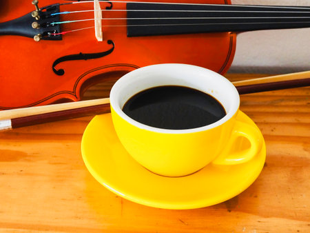 Yellow ceramic Coffeecup put beside violin and bow,on background.の写真素材