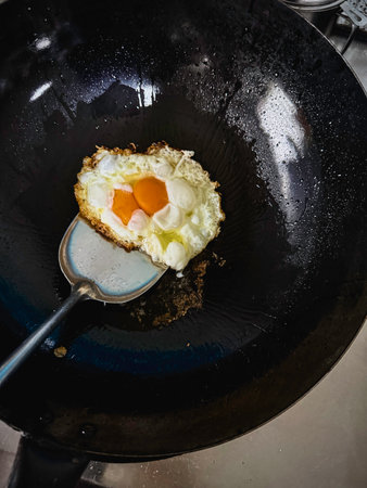 Stainless spatula scoop outSunny side fried egg in black wok,homemade cooking food for meal.の写真素材