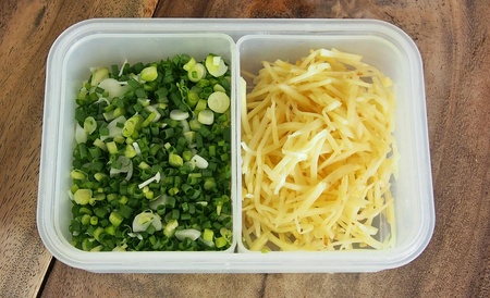 Sliced and chopped vegetable in a whitr plastic box on a wodden table.の素材