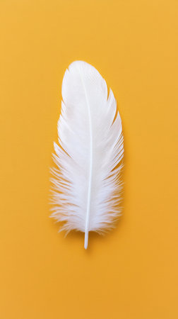 White Feather on Bright Yellow Background for Soft and Elegant Decorationの素材