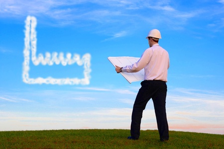 Man with plan and cloud-factory standing on a meadowの写真素材