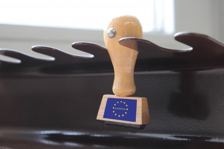 Hardwood office stamp with the emblem of the Eurozone hanging on a metal holder for stamping official documents and correspondenceの写真素材