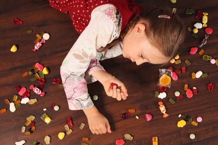Girl on floor with many sweetsの写真素材