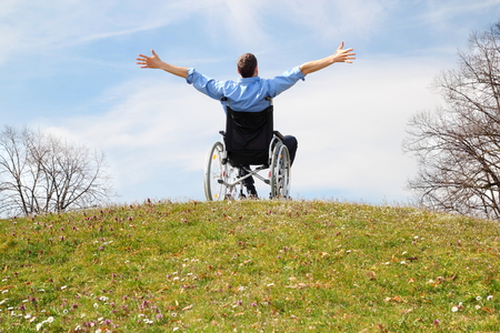 Happy Wheelchair user on a green hillの写真素材
