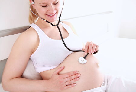 A young pregnant woman with a stethoscopeの写真素材