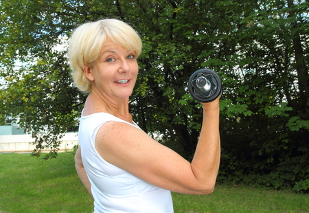 A Elderly woman doing outdoor training in a park with dumbbellの写真素材