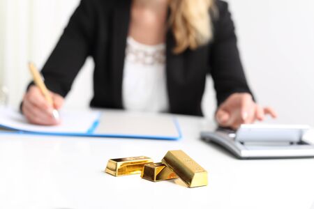 Woman with Gold Bar bullion and calculatorの写真素材