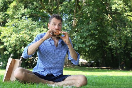 A Man enjoying his burger in a parkの写真素材