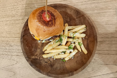 Burger with a stick and fried potato in a wooden plate serve on the table.の写真素材