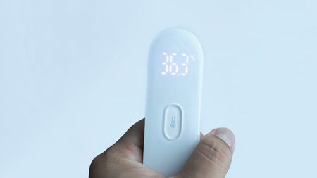 A hand holding digital thermometer showing normal temperature with isolated on white.