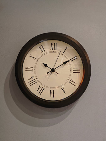 Elegant Wall Clock with Roman Numerals on Subtle Grey Backgroundの写真素材