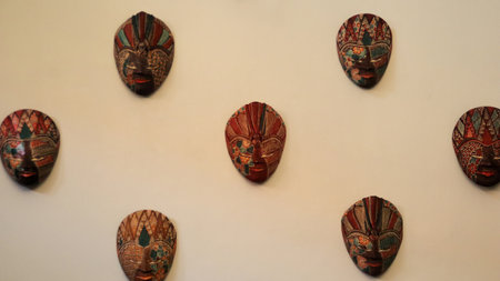 Traditional Javanese Batik Masks Displayed on a Light Beige Wall in Indonesian Cultural Exhibitionの写真素材
