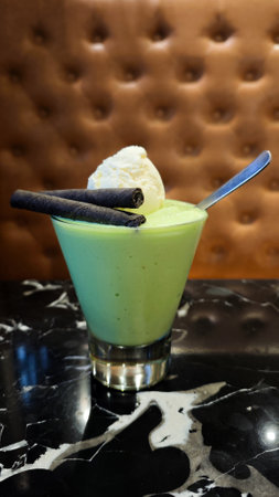Freshly Blended Avocado Juice with Ice Cream and Chocolate Wafer Sticks Topped in a Clear Glass on a Marble Tableの写真素材