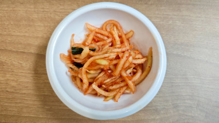 Close-Up of Korean Radish Banchan in a White Bowl on Wooden Table Backgroundの写真素材