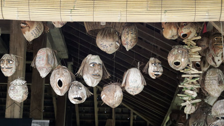 Scary Hanging Hand-Carved Coconut Faces in a Traditional Wooden Hut Interior with Natural Lightの写真素材