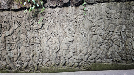 Intricately Carved Stone Wall Depicting Mythical Monkey Figures in a Lush Outdoor Setting Surrounded...
