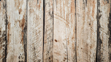 Weathered wooden planks with rustic aged texture in natural brown and beige tones forming a vertical wooden surface with visible grain knots cracks and rough imperfections in an old outdoor settingの写真素材