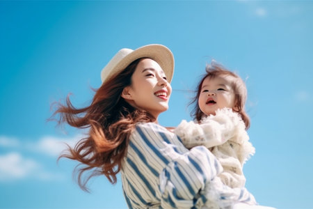 happy asian mother and daughter having fun outdoor with blue sky backgroundの素材