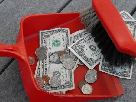 sweeping up money with a red dustpan and broomの写真素材