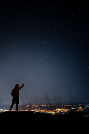 single person pointing at comet neowisse over Ourense city